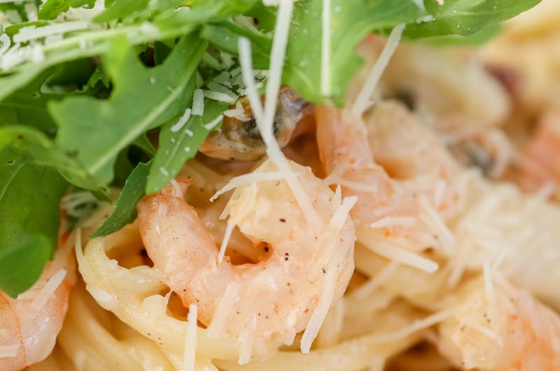 Delicious creamy shrimp pasta topped with fresh arugula and grated Parmesan cheese.